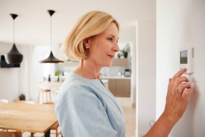 woman controlling heating using a thermostat
